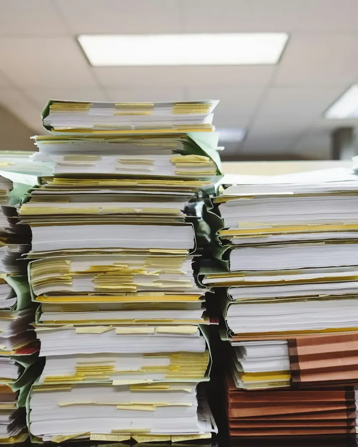 Stacks of case files with yellow flags on a desk